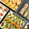R&oacute;żnorodne przekąski finger food ułożone na tacach i p&oacute;łmiskach