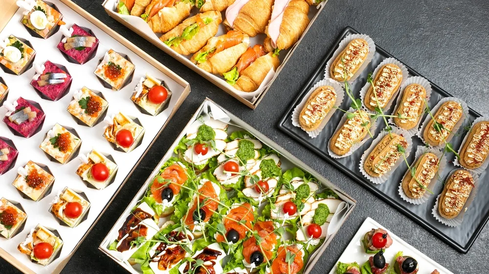 Różnorodne przekąski finger food ułożone na tacach i półmiskach